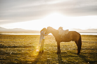 Leander Nardin, mujer joven y su caballo al atardecer (Kirguistán, Asia)