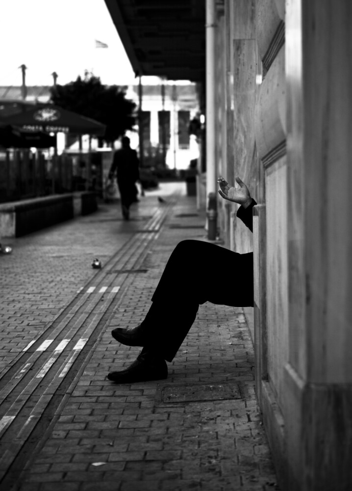Un homme qui fume à l'extérieur d'un immeuble - Photographie fineart de Nasos Zovoilis