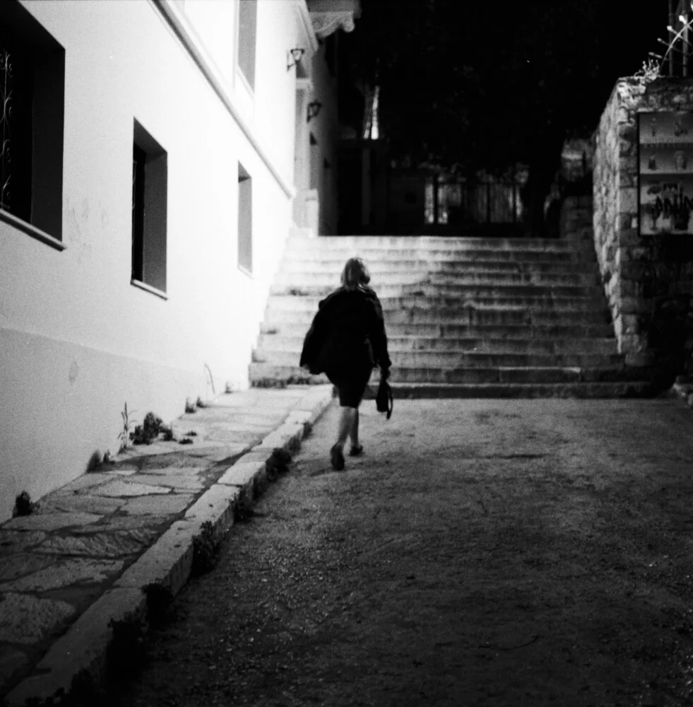 Una donna che cammina nel buio - Fotografia Fineart di Nasos Zovoilis