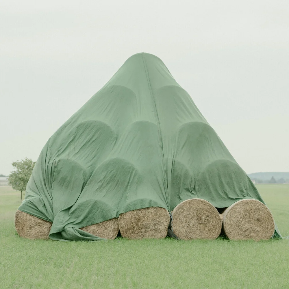 Field with hay bales in warm tones, conveying a calm rural atmosphere.