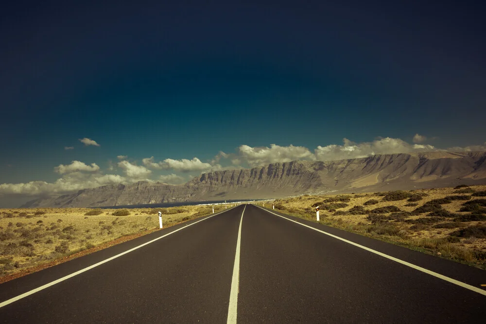 Photo art by Anke Dörschlen: road through a vast landscape under a blue sky.