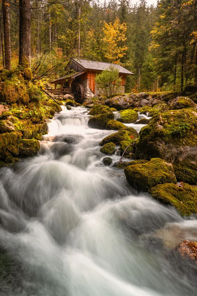 Waterfall and historic watermill in Austria surrounded by colorful autumn leaves.