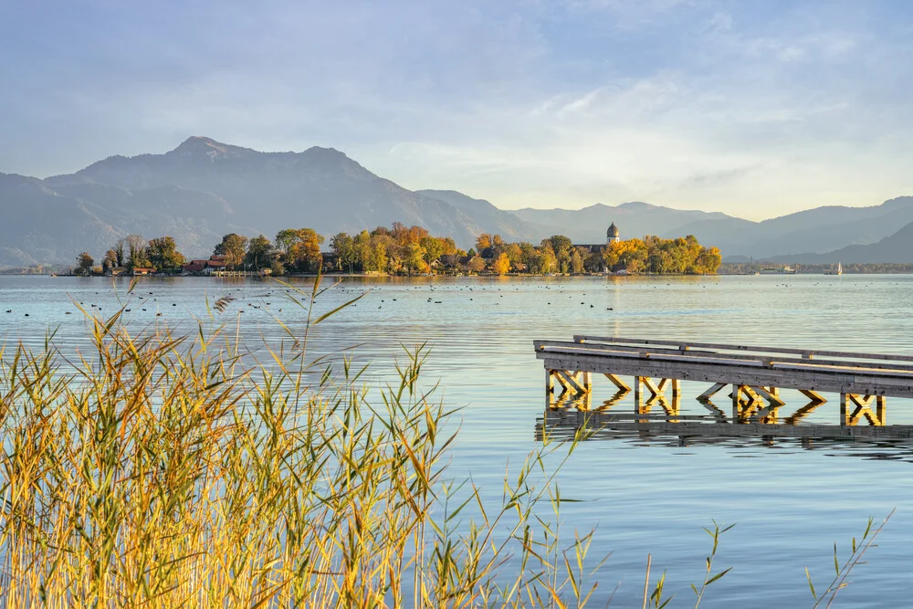Beautiful view of Lake Chiemsee featuring Fraueninsel at sunset with soft clouds.