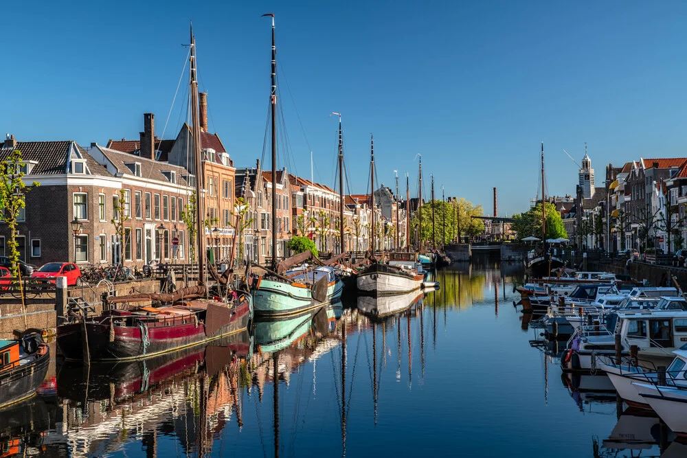Harbor view of Delfshaven in Rotterdam featuring a sailing boat and calm water reflection