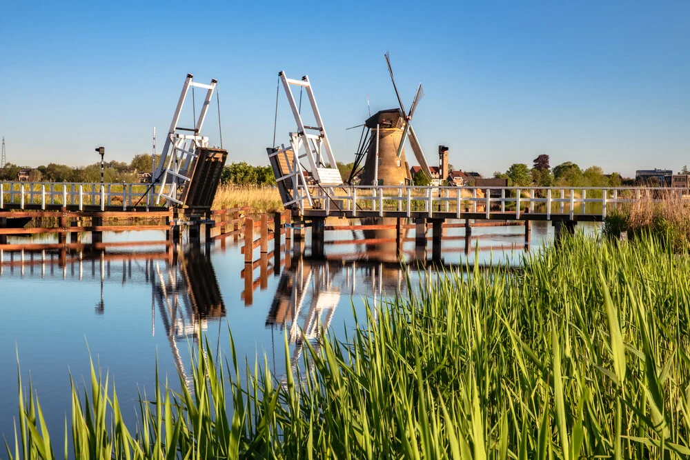 Morning scene in Southern Holland featuring windmills and gentle reflections in the water.