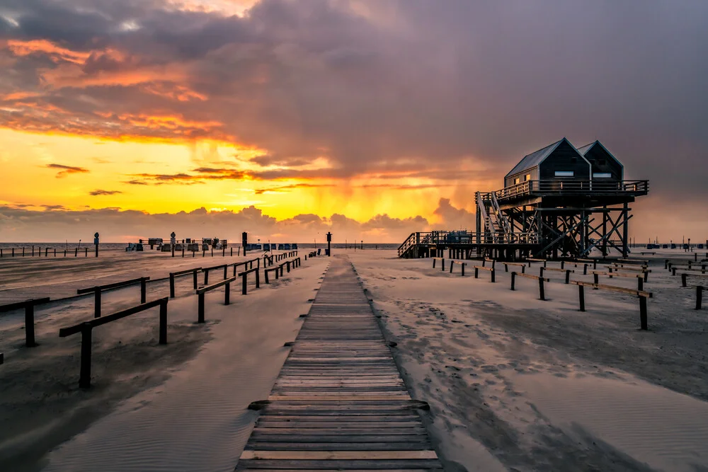 Beautiful sunset over the North Sea with gentle waves and wooden jetties.
