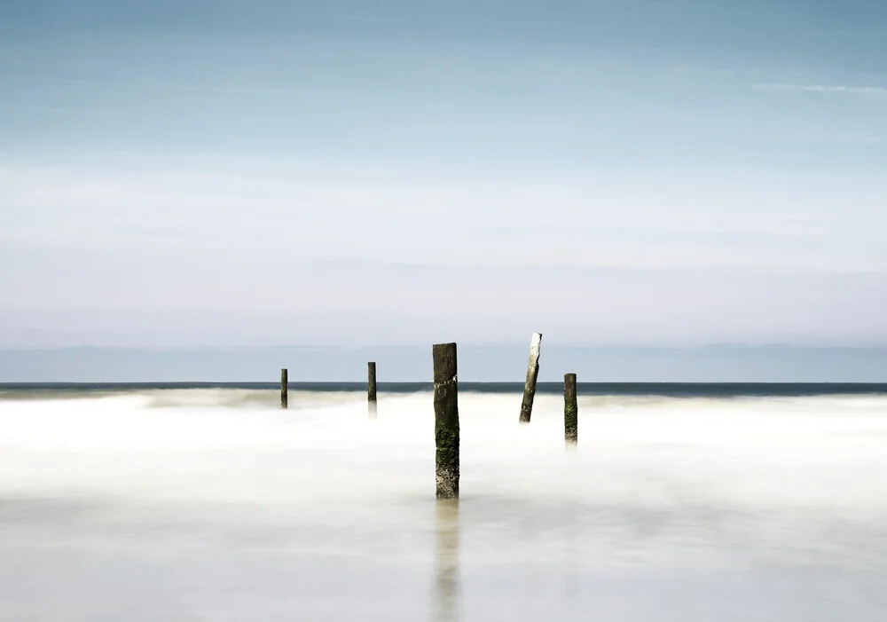 Fotokunst von Manuela Deigert: ruhige Küstenaufnahme mit Holzpfählen und sanften Wellen