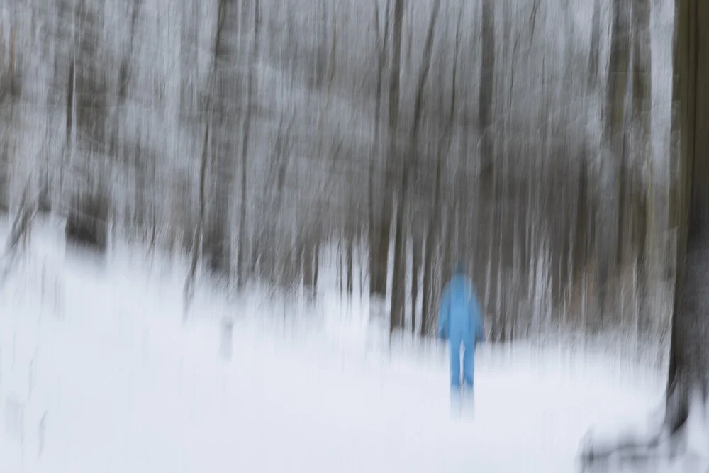 Verwischter Winterwald mit Spaziergängerin, sanfte Bewegungen im Schnee.