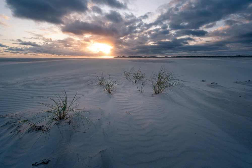 Sunset at Kniepsand beach on Amrum featuring clouds and gentle sand dunes.