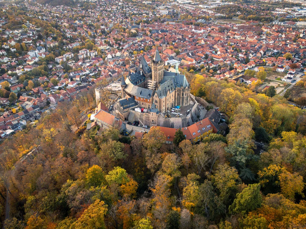Aerial view of Wernigerode Castle in autumn, surrounded by colorful leaves.