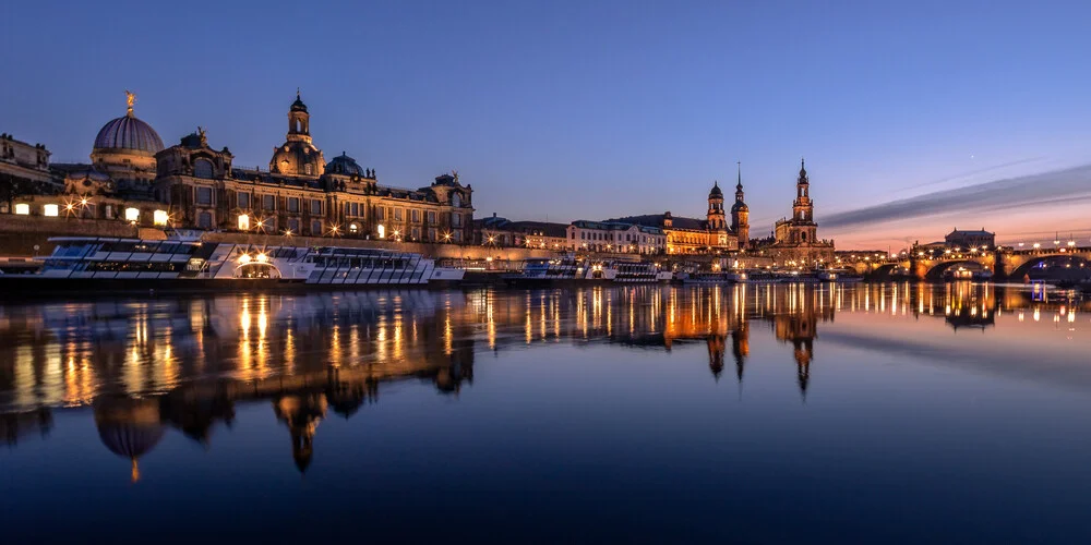 Dresden bei Nacht: beleuchtete Silhouette von Semperoper und Frauenkirche am Elbufer.