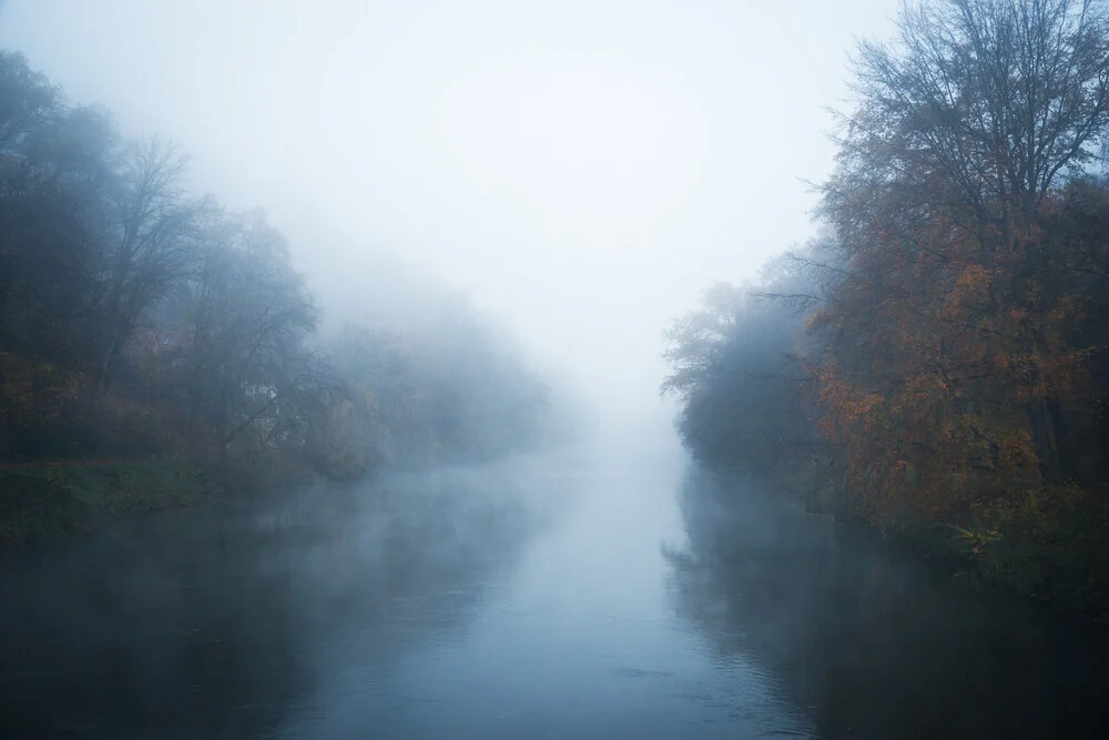 Morgens am Fluss: ruhige Wasseroberfläche im Nebel mit herbstlichen Farben.