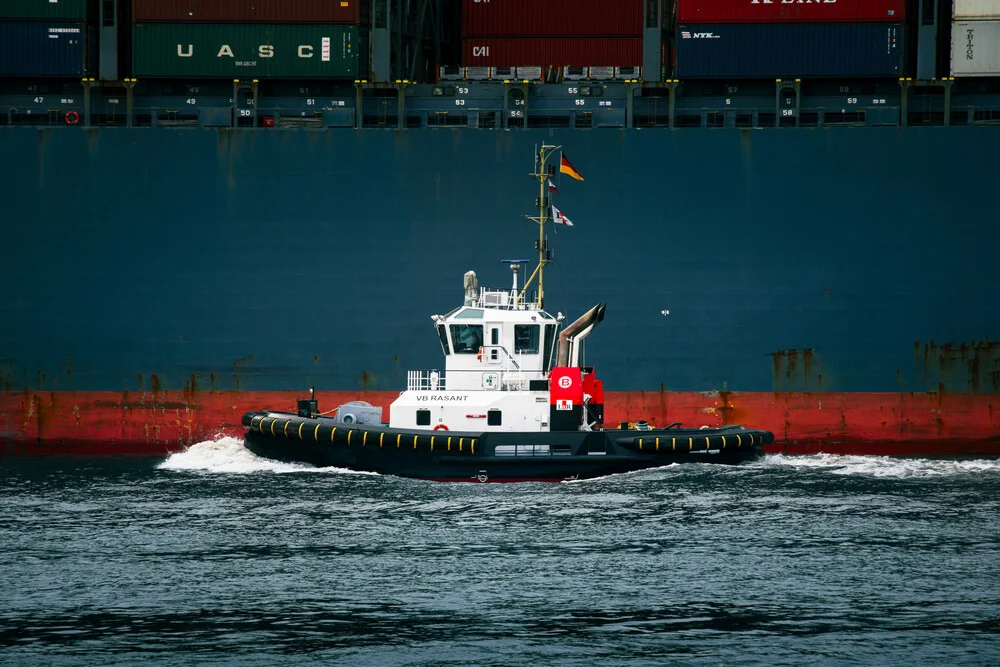 Schlepper auf der Elbe: ruhige Hafenatmosphäre mit Containerschiff im Hintergrund