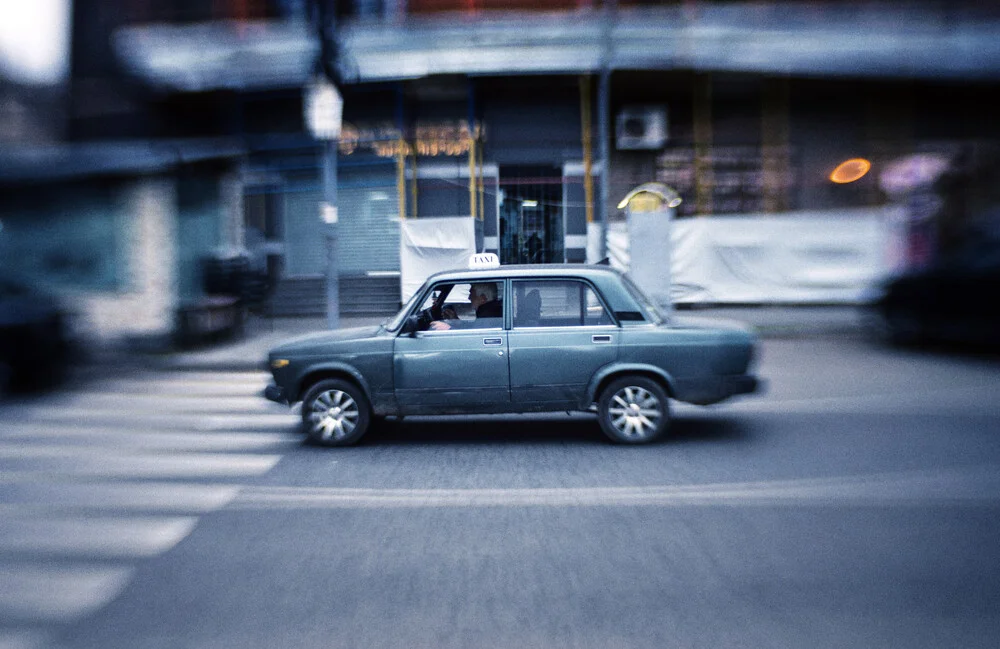 Blue taxi on a busy street in Armenia, capturing a moment of urban life.