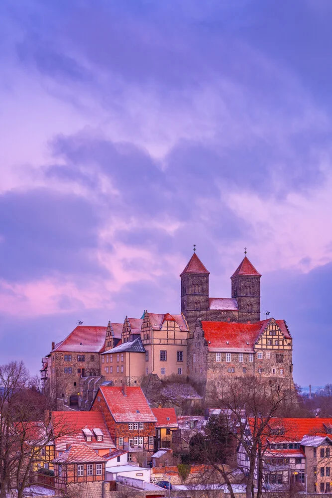A winter view of Quedlinburg with snow-covered rooftops and the castle.