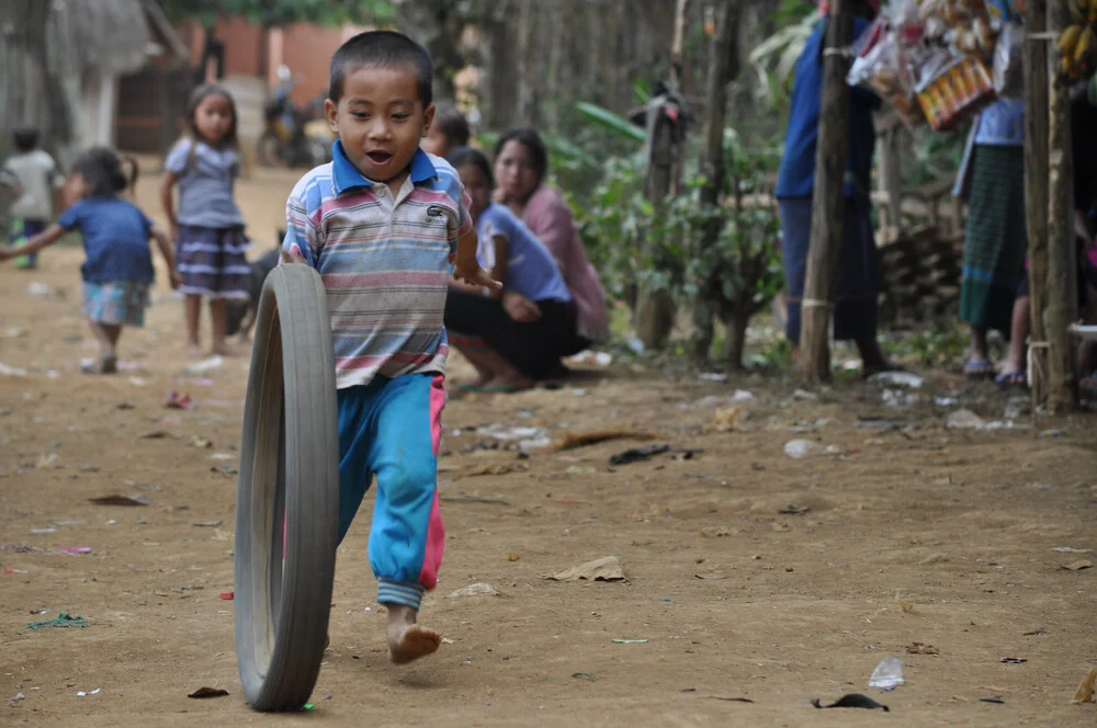 Boy playing with a tire - fotokunst von Thomas Heinrich