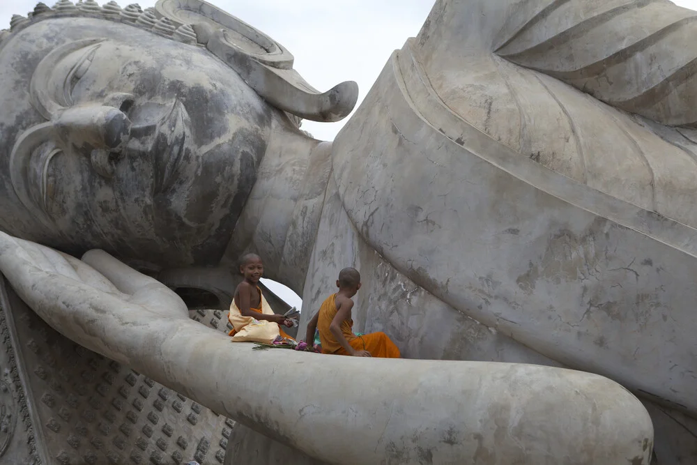 Monks sitting on big Buddha statue, Laos - Fineart photography by Christina Feldt