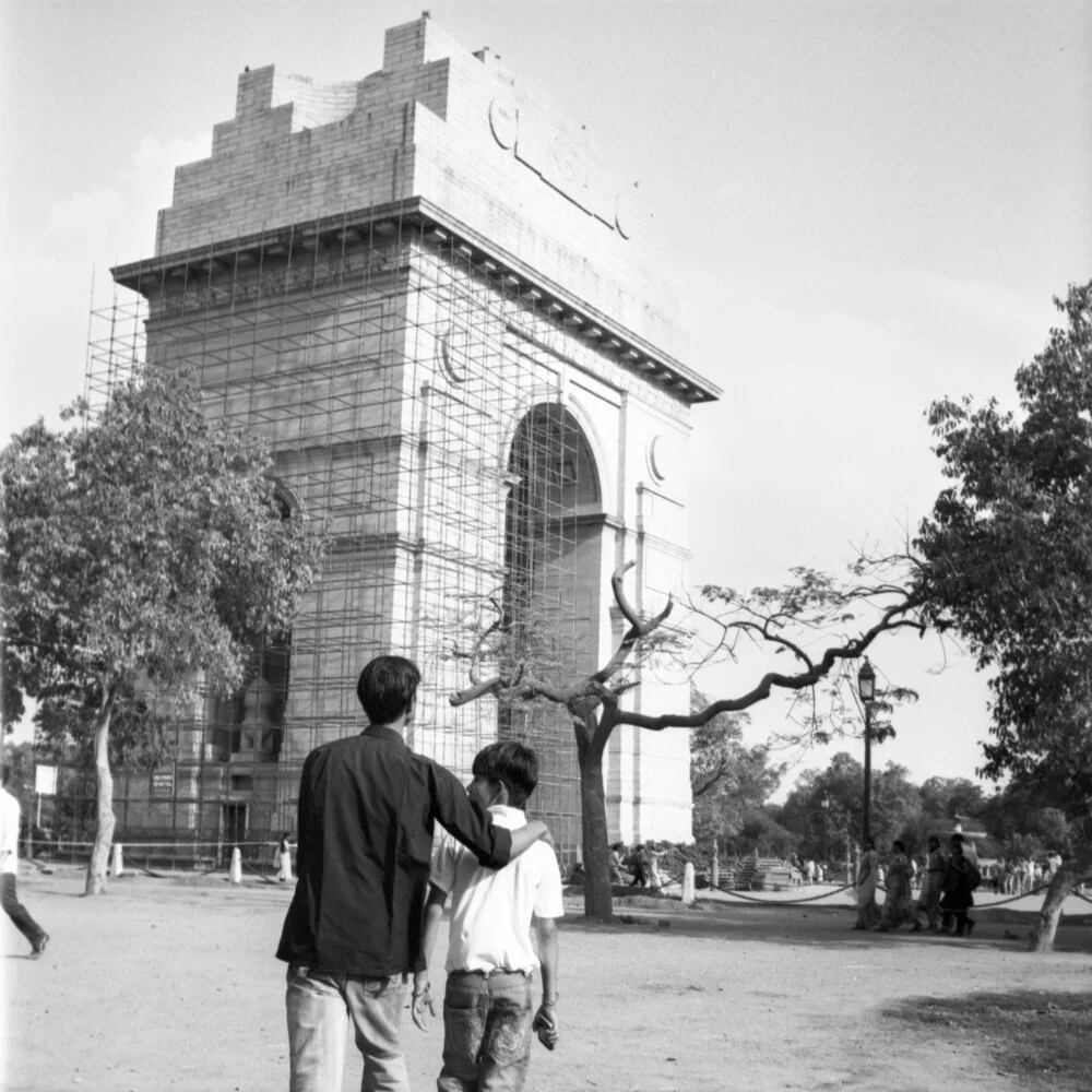 Zwei Jungs gehen vor dem India Gate in Neu Delhi spazieren.  - fotokunst von Shantala Fels