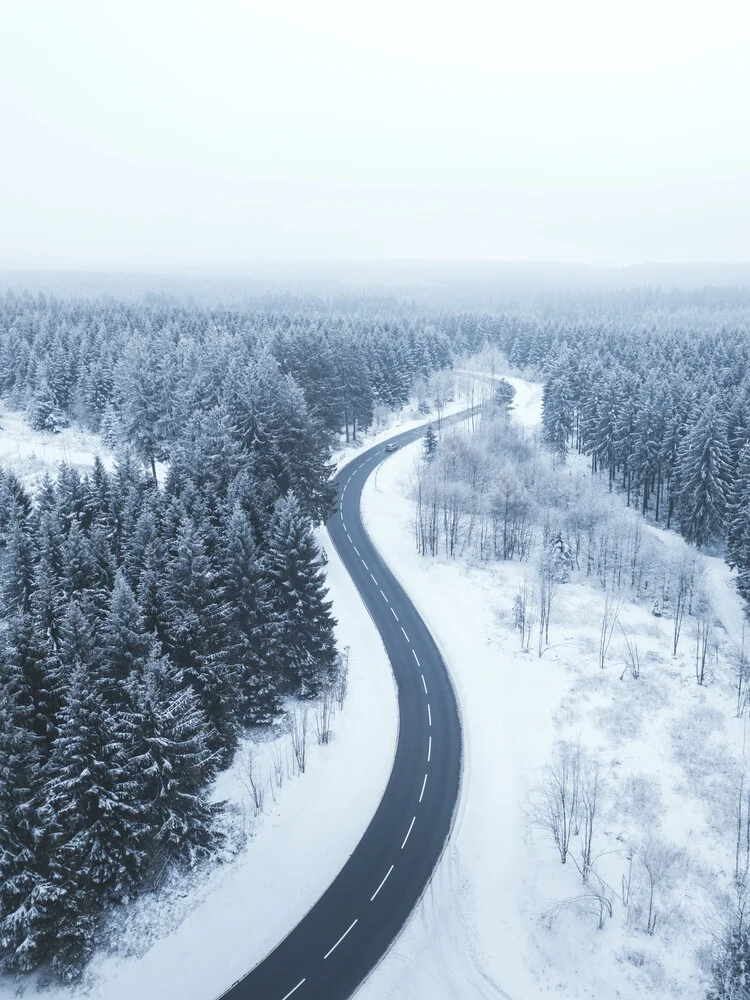 Snowy road through forest in winter - Fineart photography by Lukas Saalfrank