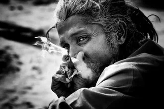 Wall art of a Sadhu relaxing while smoking a joint in soft colors.