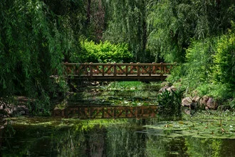 Fotokunst von AJ Schokora: üppige grüne Parklandschaft mit ruhiger Brücke