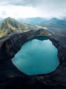 Luftaufnahme eines Kratersees in Island, umgeben von vulkanischen Felsen.