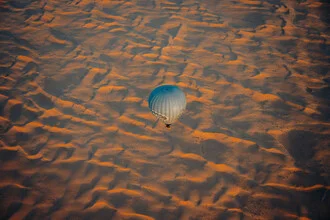 Heißluftballon über der Wüste bei Sonnenaufgang, ruhige und friedliche Stimmung.