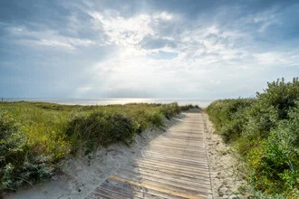 Path to the beach with wooden planks, surrounded by gentle waves and a clear sky.