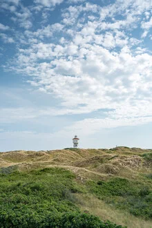 Wasserturm auf Langeoog im Sommer, umgeben von Dünen und klarem Himmel.