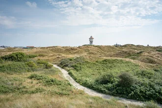 Wasserturm auf Langeoog vor einem klaren blauen Himmel und grünen Dünen.