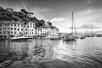 Portofino harbor view at sunrise with gentle waves and boats on the water.