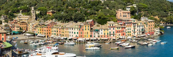 Colorful house facades in the fishing village of Portofino, Italy, under a blue sky.