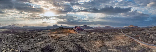 Photo of a volcano in Lanzarote, showcasing the barren landscape and the sun.