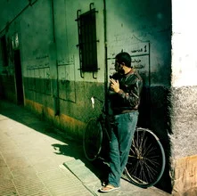 Man at a street corner in Essaouira, Morocco, with a bicycle nearby.