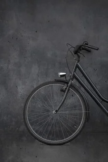 Black vintage bike against a concrete wall, radiating a minimalist charm.