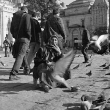 Photo of a smoker in the city, surrounded by pigeons, warm light and a friendly mood.