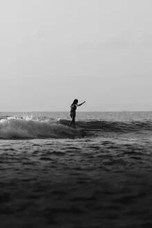 Woman on a surfboard in the ocean, black and white photo with a calm mood.