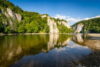 Sommerliche Landschaft am Donauriver, sanfte Hügel und klare Wasseroberfläche.