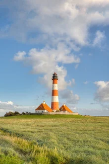 Charming Westerheversand lighthouse against soft clouds and green grass in Northern Germany