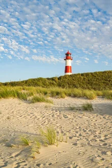 Sommerabend auf Sylt mit sanften Dünen und einem Leuchtturm im Abendlicht.