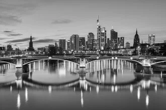 Schwarzweißaufnahme von Frankfurt am Abend mit beleuchteten Hochhäusern.