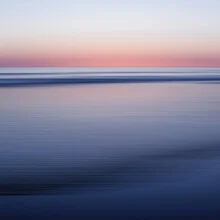 Calm seascape with gentle waves and a pink sunset.