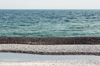 Photos by Manuela Deigert: calm pebble beach with gentle waves and clear sky