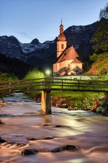 Evening scene in Ramsau featuring a lit church and calm river