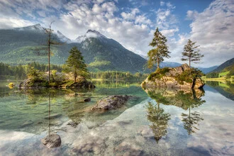Morning sun at Hintersee lake in Bavaria, calm water surface and gentle mountain backdrop.