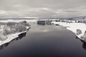 Aerial view of a serene winter landscape featuring a glistening lake