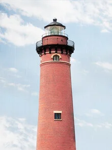Bright red lighthouse against a clear sky and calm seaside landscape.