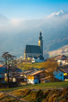Winterlandschaft in Anger mit schneebedeckten Bergen und einer Kirche im Hintergrund.