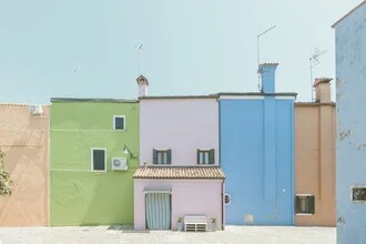 Photographic depiction of a white bench by the water in Burano, Italy.