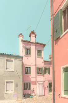 Colorful garden gnomes against pastel houses in Burano, Italy.